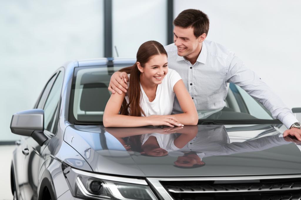 Happy young couple admiring their new car